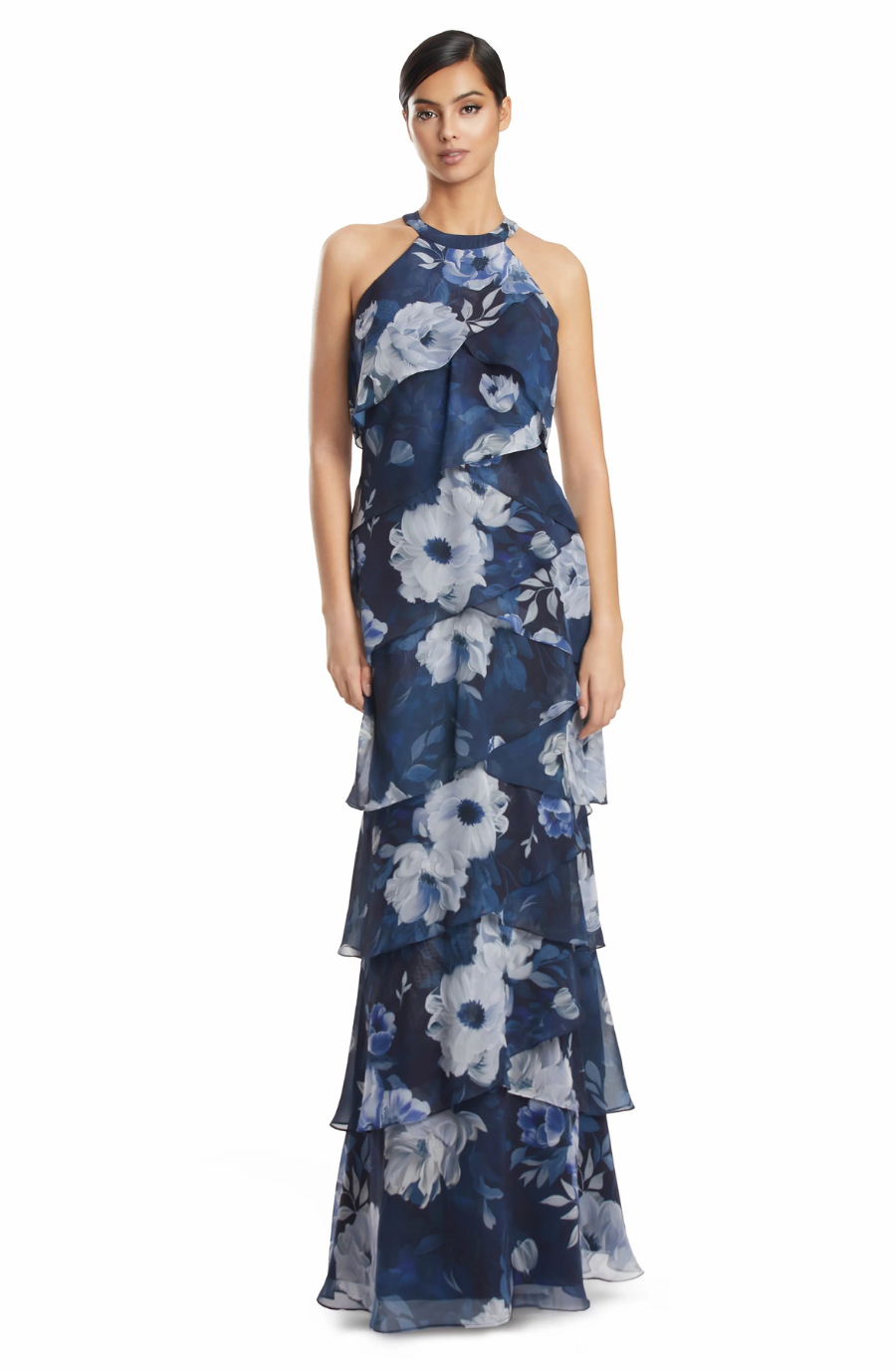 A woman wearing a sleeveless, floral-patterned navy blue gown with layered ruffles.