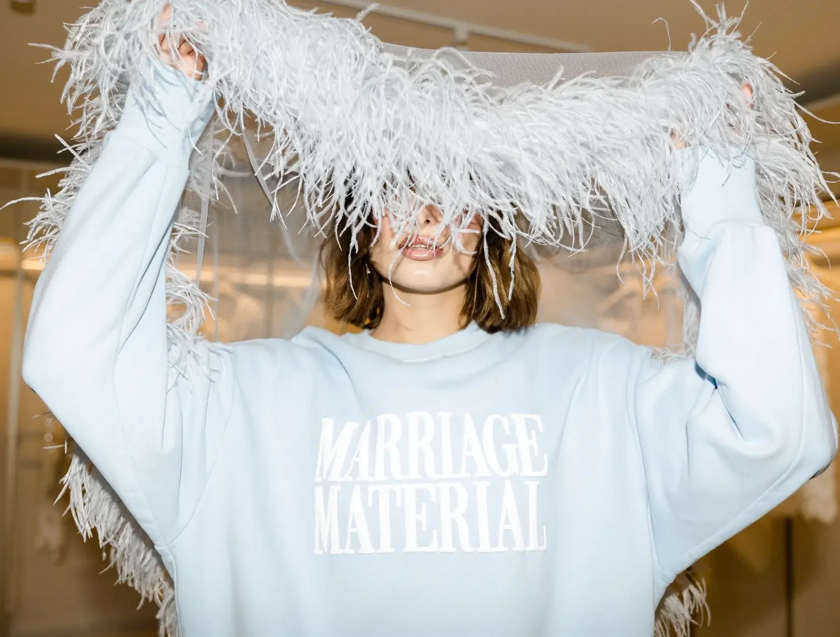 model is wearing an oversized sweatshirt by bridemerch that says marriage material