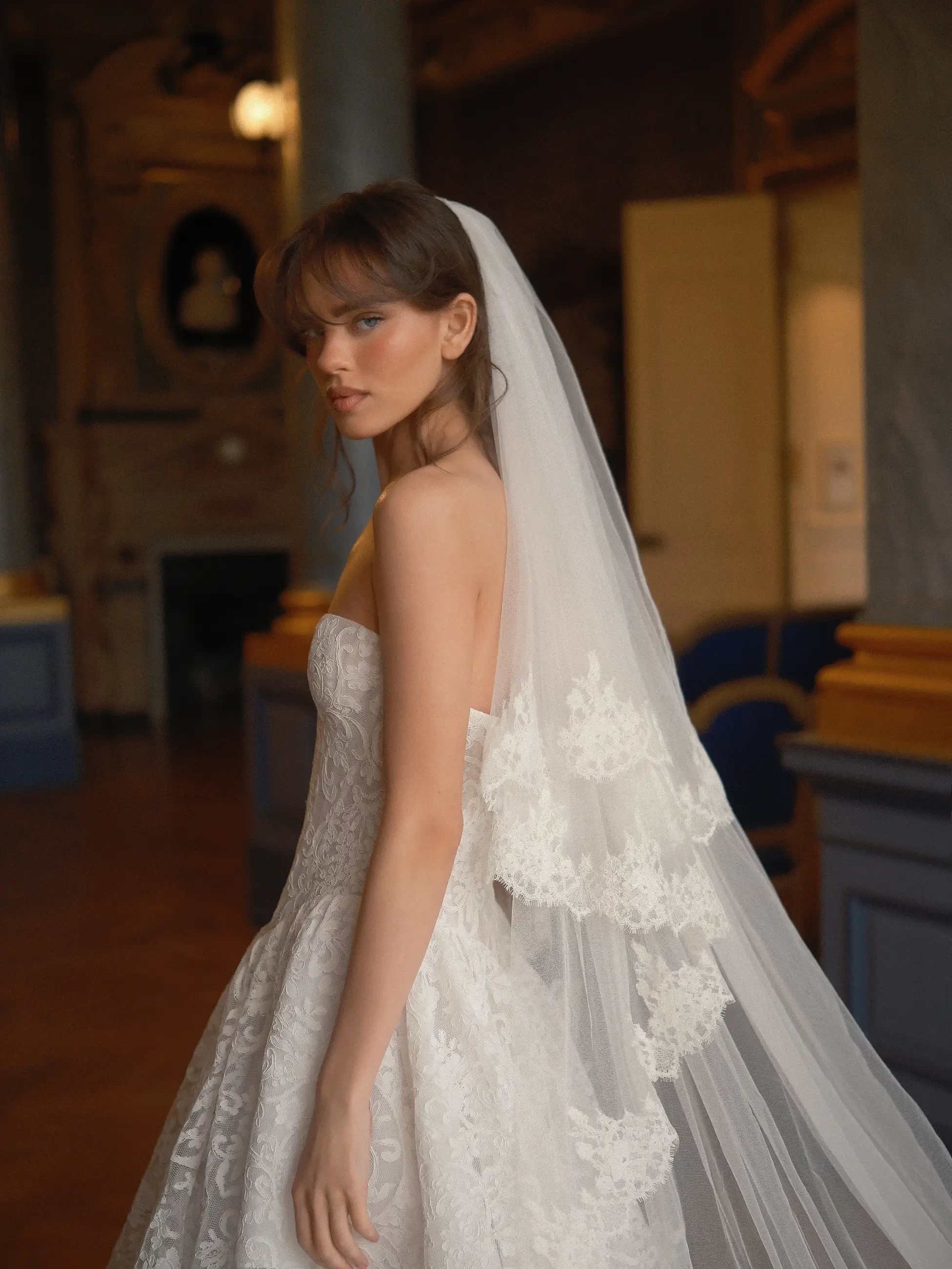 model is wearing a strapless bridal gown with a veil