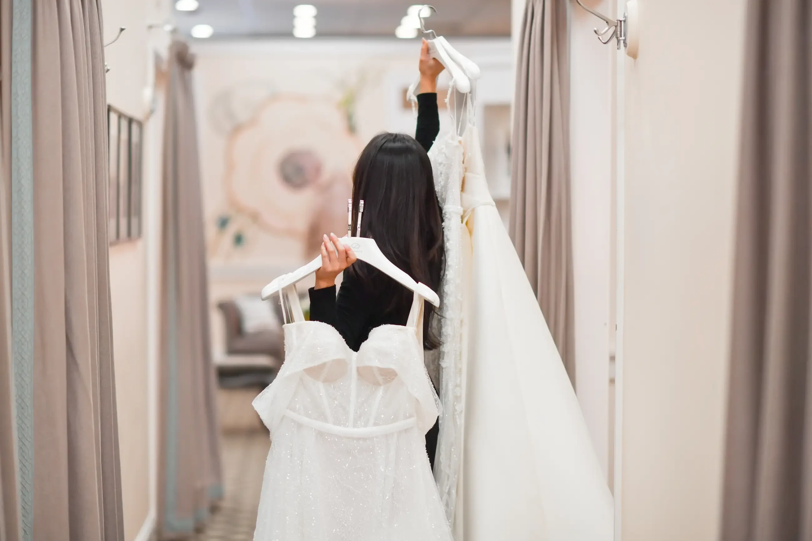 image shows a bridal stylist pulling gowns