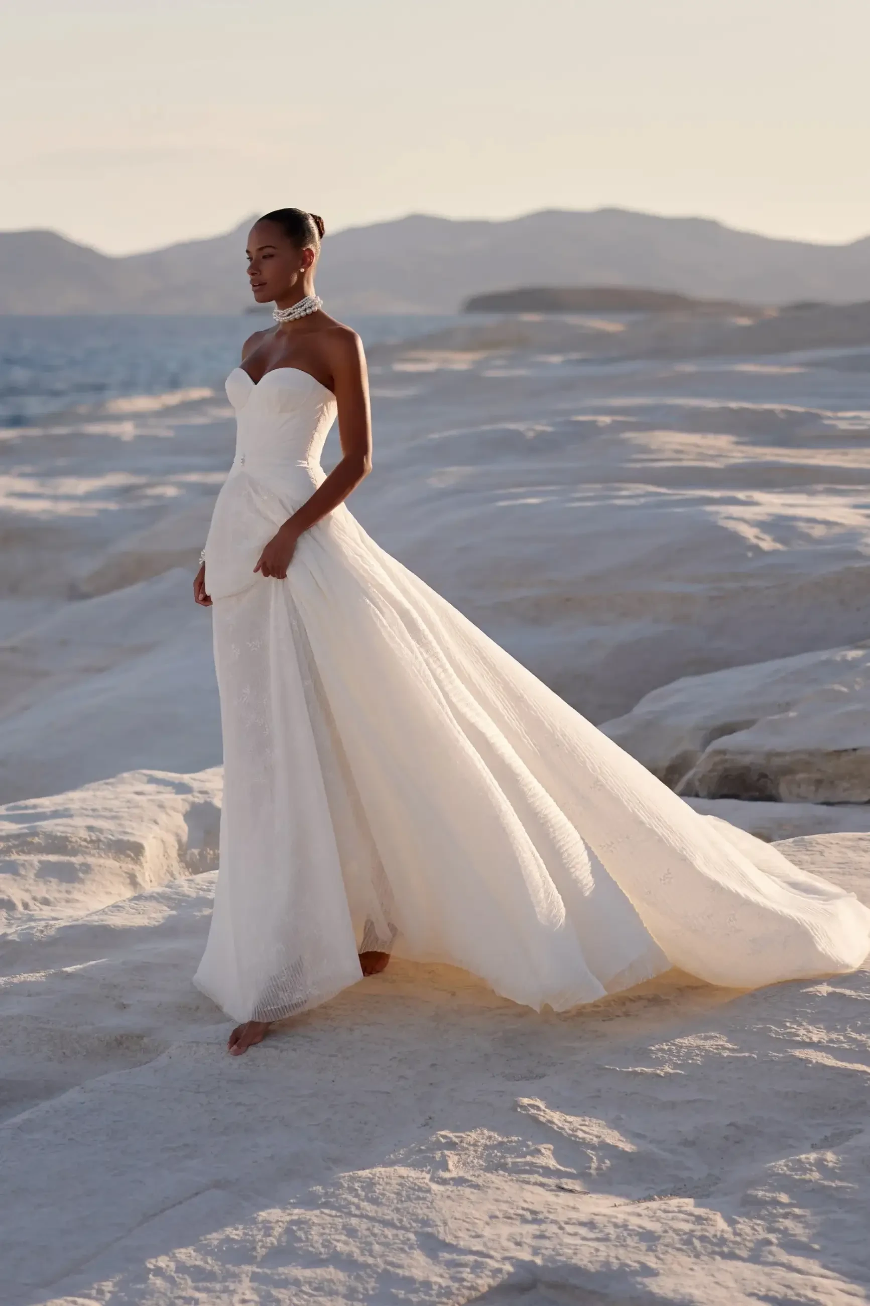 Model wears a heart-shaped neckline gown with a sheer corset bodice and pearl-embellished skirt.