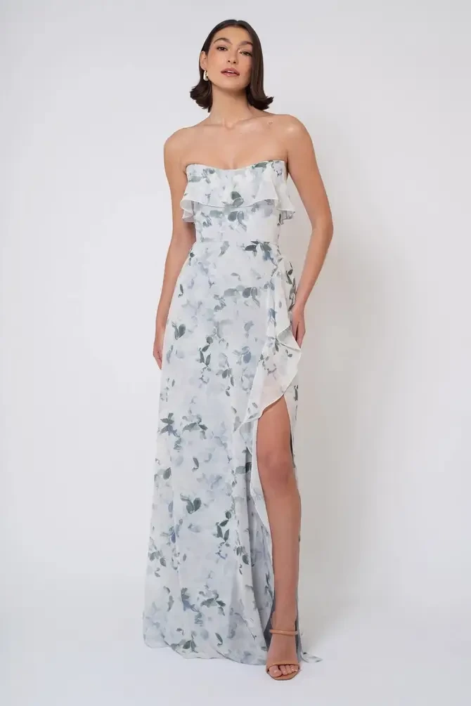 model is wearing a strapless floral bridesmaid dress with a slit
